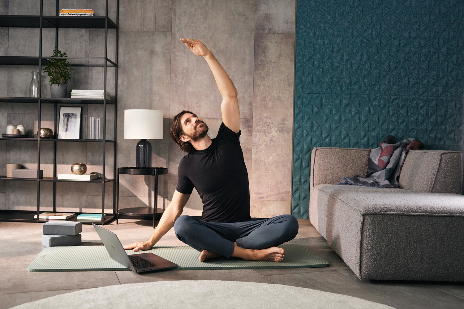 homme faisant du yoga sur un tapis avec son ordi